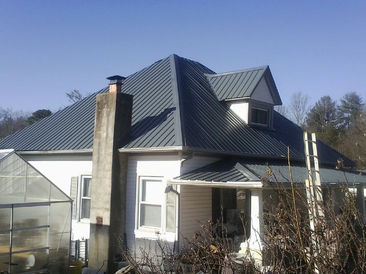 Dark blue standing seam metal roof on a white farmhouse with dormer — Slate & Tile Roof Repair by Roofing Brothers in Avoca