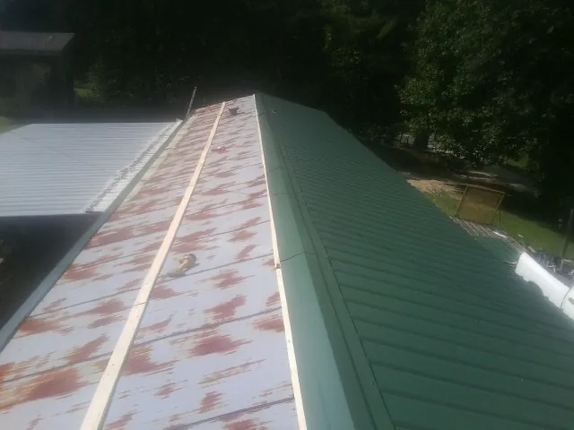 Old rusted panels beside newly installed green metal roofing — Wind Damage Roof Repair by Roofing Brothers in Avoca