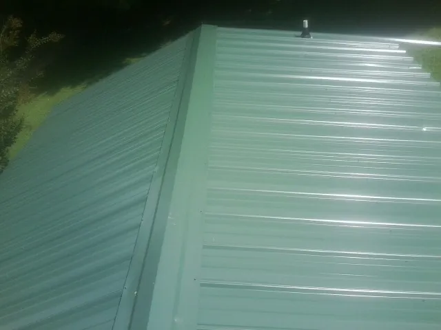 New green metal panels meeting at the ridge of a roof — Flat Roof Repair work by our crew in Avoca